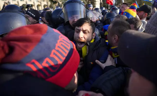 Riot police scuffle with supporters of Calin Georgescu, the winner of Romania's first round of presidential election which the Constitutional Court later annulled, who broke through police lines in front of the government headquarters, in Bucharest, Romania, Monday, Feb. 10, 2025. (AP Photo/Vadim Ghirda)