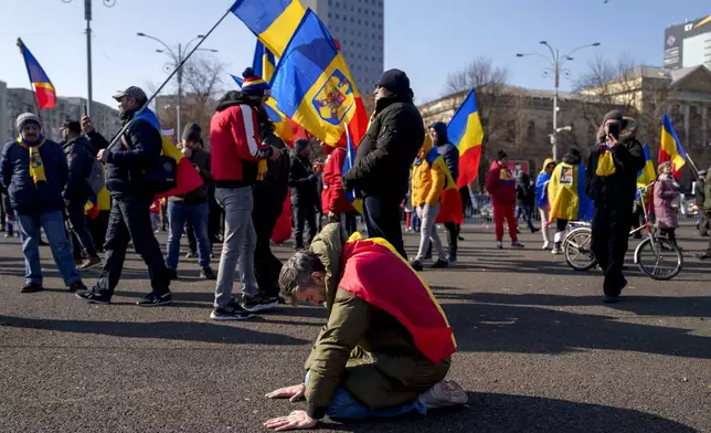 A man prays while kneeling during a protest by supporters of Calin Georgescu, the winner of Romania's first round of presidential election which the Constitutional Court later annulled, in Bucharest, Romania, Monday, Feb. 10, 2025. (AP Photo/Vadim Ghirda)