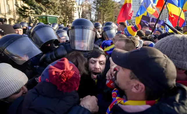 Riot police scuffle with supporters of Calin Georgescu, the winner of Romania's first round of presidential election which the Constitutional Court later annulled, who broke through police lines in front of the government headquarters, in Bucharest, Romania, Monday, Feb. 10, 2025. (AP Photo/Vadim Ghirda)