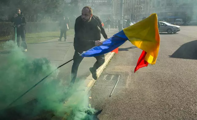 A man holding a Romanian flag runs after breaking through police lines in front of the government headquarters during a protest by supporters of Calin Georgescu, the winner of Romania's first round of presidential election which the Constitutional Court later annulled, in Bucharest, Romania, Monday, Feb. 10, 2025. (AP Photo/Vadim Ghirda)