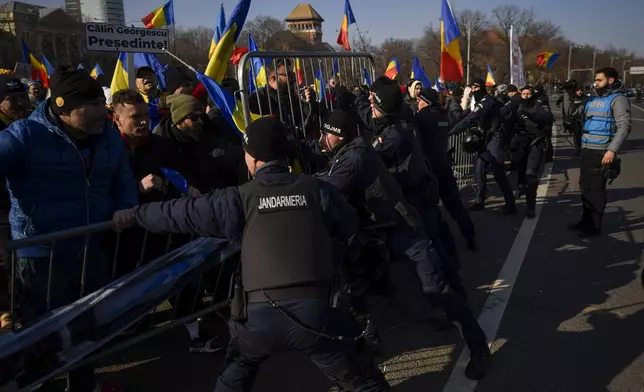 Riot police scuffle with supporters of Calin Georgescu, the winner of Romania's first round of presidential election which the Constitutional Court later annulled, who broke through police lines in front of the government headquarters, in Bucharest, Romania, Monday, Feb. 10, 2025. (AP Photo/Alexandru Dobre)