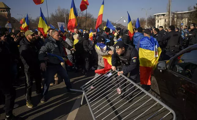 Riot police scuffle with supporters of Calin Georgescu, the winner of Romania's first round of presidential election which the Constitutional Court later annulled, who broke through police lines in front of the government headquarters, in Bucharest, Romania, Monday, Feb. 10, 2025. (AP Photo/Alexandru Dobre)