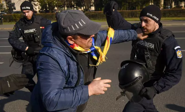 Riot police scuffle with supporters of Calin Georgescu, the winner of Romania's first round of presidential election which the Constitutional Court later annulled, who broke through police lines in front of the government headquarters, in Bucharest, Romania, Monday, Feb. 10, 2025. (AP Photo/Alexandru Dobre)