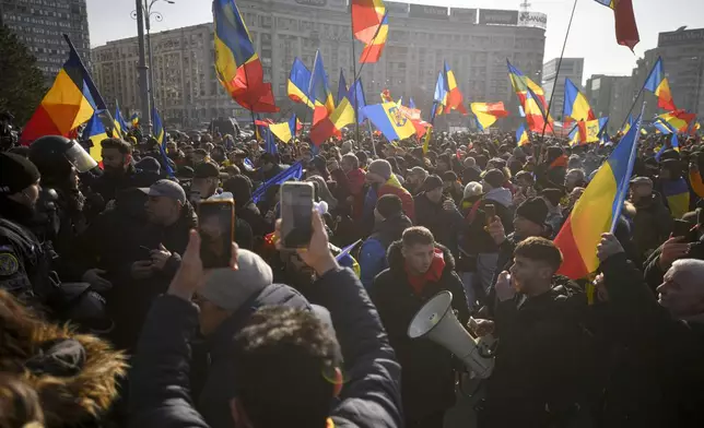 Supporters of Calin Georgescu, the winner of Romania's first round of presidential elections, wave flags and chant slogans in front of the government headquarters, in Bucharest, Romania, Monday, Feb. 10, 2025. (AP Photo/Alexandru Dobre)