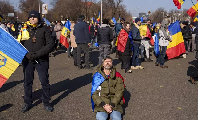 A man prays while kneeling during a protest by supporters of Calin Georgescu, the winner of Romania's first round of presidential election which the Constitutional Court later annulled, in Bucharest, Romania, Monday, Feb. 10, 2025. (AP Photo/Vadim Ghirda)