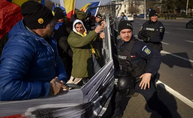 Riot police scuffle with supporters of Calin Georgescu, the winner of Romania's first round of presidential election which the Constitutional Court later annulled, who broke through police lines in front of the government headquarters, in Bucharest, Romania, Monday, Feb. 10, 2025. (AP Photo/Alexandru Dobre)