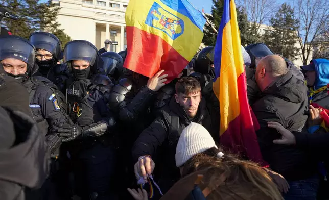 Riot police scuffle with supporters of Calin Georgescu, the winner of Romania's first round of presidential election which the Constitutional Court later annulled, who broke through police lines in front of the government headquarters, in Bucharest, Romania, Monday, Feb. 10, 2025. (AP Photo/Vadim Ghirda)