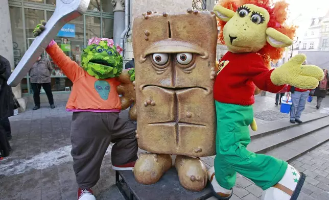 FILE - The puppet characters on the German children's television channel 'Kika' 'Briegel der Busch', left, and 'Chilie das Schaf', right, present the statue "Bernd das Brot" at his regular place in front of the City hall in Erfurt, Germany, Wednesday, Feb. 4, 2009. (AP Photo/Jens Meyer, File)