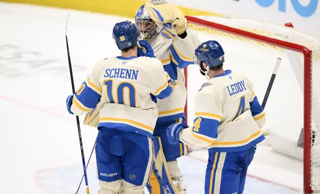 St. Louis Blues goaltender Joel Hofer, back, celebrates with center Brayden Schenn (10) and defenseman Nick Leddy (4) after an NHL hockey game against the Washington Capitals, Thursday, Feb. 27, 2025, in Washington. (AP Photo/Nick Wass)