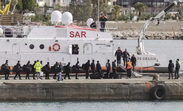 Migrants board an Italian Coast Guard vessel as part of a transfer operation from the asylum processing centers in Albania back to Italy following a court decision in Rome, at the port of Shengjin, northwestern Albania, Saturday, Feb. 1, 2025. (AP Photo/Vlasov Sulaj)