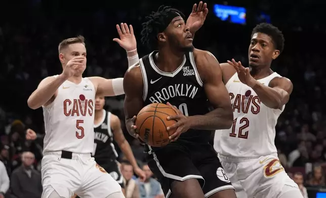 Cleveland Cavaliers' De'Andre Hunter (12) and Sam Merrill (5) defend Brooklyn Nets' Day'Ron Sharpe (20) during the second half of an NBA basketball game Thursday, Feb. 20, 2025, in New York. (AP Photo/Frank Franklin II)