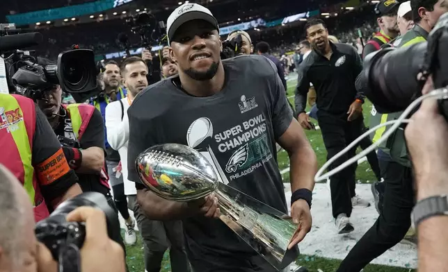 Philadelphia Eagles running back Saquon Barkley carries the Vince Lombardi Trophy after the NFL Super Bowl 59 football game against the Kansas City Chiefs, Sunday, Feb. 9, 2025, in New Orleans. (AP Photo/Ashley Landis)