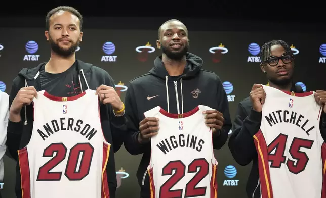 Newly signed Miami Heat basketball players Kyle Anderson (20), Andrew Wiggins (22) and Davion Mitchell (45) hold up their jerseys during a news conference Sunday, Feb. 9, 2025, in Miami. (AP Photo/Lynne Sladky)