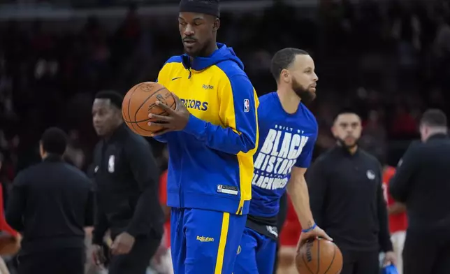 Golden State Warriors forward Jimmy Butler, left, and guard Stephen Curry, right, warm up before an NBA basketball game against the Chicago Bulls, Saturday, Feb. 8, 2025, in Chicago. (AP Photo/Erin Hooley)