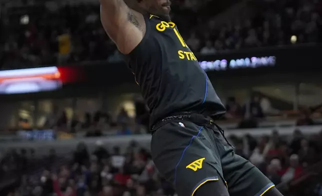 Golden State Warriors forward Jimmy Butler hangs from the rim after dunking during the second half of an NBA basketball game against the Chicago Bulls, Saturday, Feb. 8, 2025, in Chicago. (AP Photo/Erin Hooley)