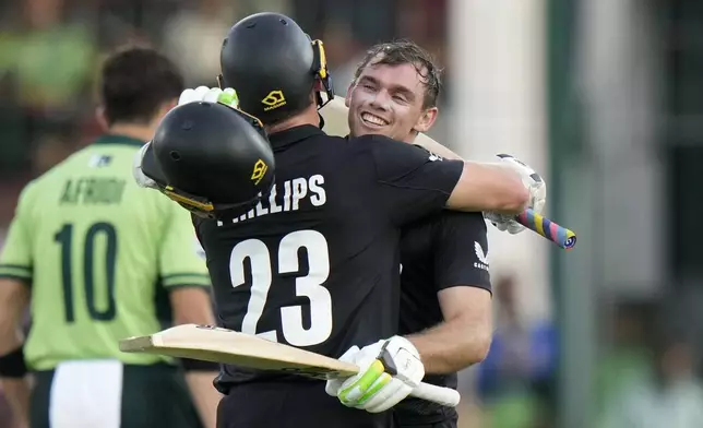 New Zealand's Tom Latham, right, celebrates with Glenn Phillips after scoring century during the ICC Champions Trophy cricket match between Pakistan and New Zealand, in Karachi, Pakistan Wednesday, Feb. 19, 2025. (AP Photo/Anjum Naveed)