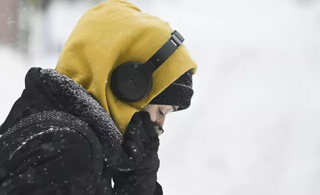 A person covers up during a snowstorm in Montreal, Sunday, Feb. 16, 2025. (Graham Hughes/The Canadian Press via AP)