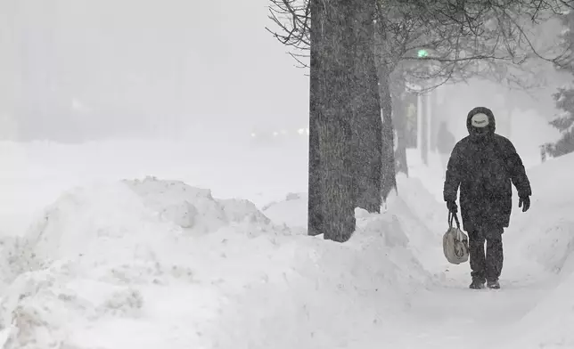 A person covers up during a snowstorm in Montreal, Sunday, Feb. 16, 2025. (Graham Hughes/The Canadian Press via AP)
