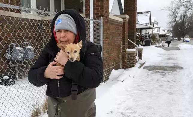 Lisa Muscat carries her dog Zoey to safety after a water main break in Detroit caused massive flooding, triggering evacuations, Monday, Feb. 17, 2025. (Andy Morrison/Detroit News via AP)