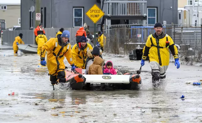 Members of the Downriver Dive Team rescue a family after a water main break in Detroit caused massive flooding, triggering evacuations, Monday, Feb. 17, 2025. (Andy Morrison/Detroit News via AP)