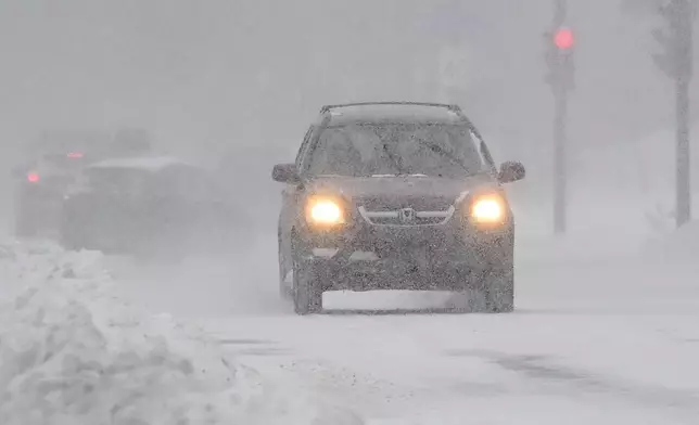 Motorists make their way along a city street during a snowstorm in Montreal, Sunday, Feb. 16, 2025. (Graham Hughes/The Canadian Press via AP)