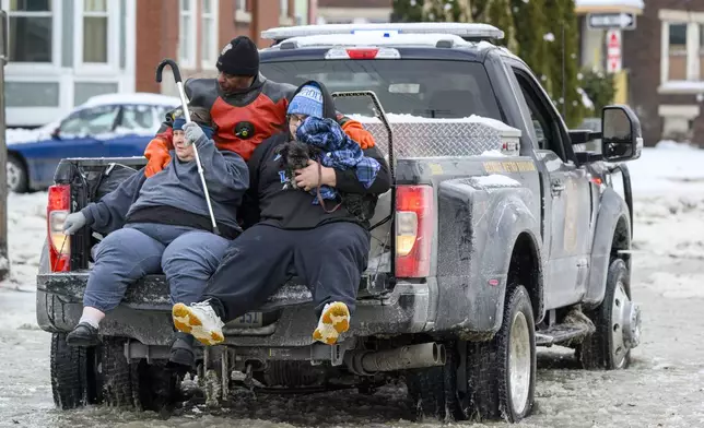 A man, woman and dog are driven to safety in a Detroit Police Department truck after a water main break in Detroit caused massive flooding, triggering evacuations, Monday, Feb. 17, 2025. (Andy Morrison/Detroit News via AP)