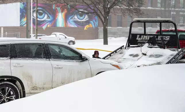 Adam O'Neil, from Limitless Recovery and Towing hooks up a vehicle Sunday, Feb. 16, 2025, on Park Street in Lewiston, Maine, as many vehicles were towed during a parking ban due to the snowstorm that blanketed the region. (Russ Dillingham/Sun Journal via AP)