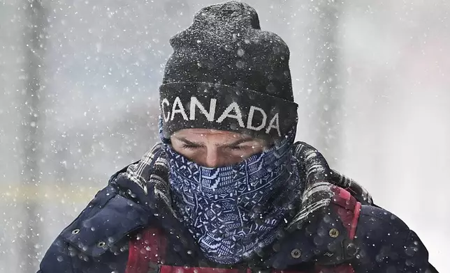 A person covers up during a snowstorm in Montreal, Sunday, Feb. 16, 2025. (Graham Hughes/The Canadian Press via AP)