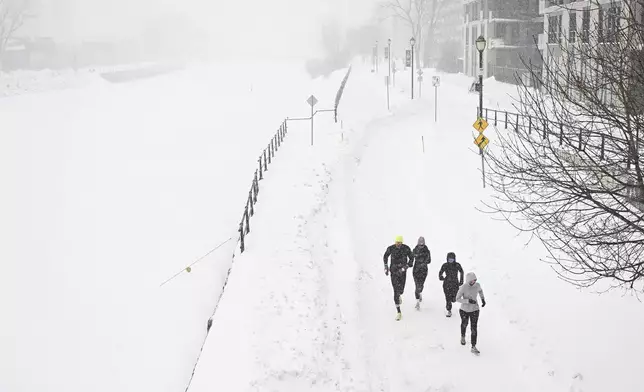 People jog along the Lachine Canal during a snowstorm in Montreal, Sunday, Feb. 16, 2025. (Graham Hughes/The Canadian Press via AP)