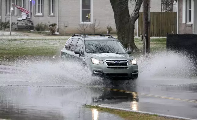 A vehicle drives through flood waters Sunday, Feb. 16, 2025, in Clarksville, Tenn. (AP Photo/George Walker IV)