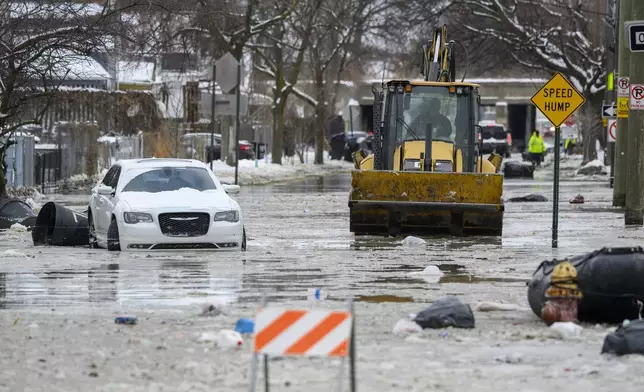 A front end loader pushes down Green Street after a water main break in Detroit caused massive flooding, triggering evacuations, Monday, Feb. 17, 2025. (Andy Morrison/Detroit News via AP)