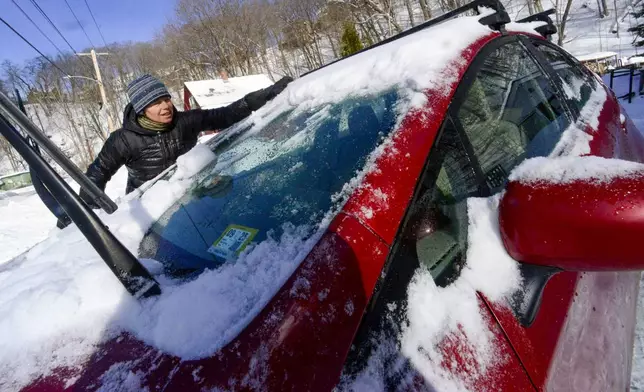 Kathy Carr uses her hands to remove the ice chunks on her vehicle on Monday, Feb. 17, 2025, Brattleboro, Vt. after a winter storm on Sunday. (Kristopher Radder/The Brattleboro Reformer via AP)