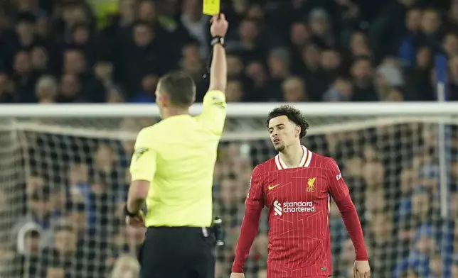 Referee Michael Oliver shows a yellow card to Liverpool's Curtis Jones, right, during the English Premier League soccer match between Everton and Liverpool, Liverpool, England, Wednesday, Feb.12, 2025. (AP Photo/Dave Thompson)