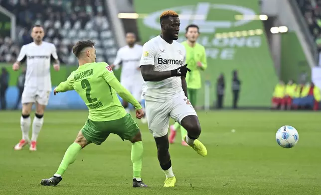Leverkusen's Victor Boniface, right, plays against Wolfsburg's Kilian Fischer during the German Bundesliga soccer match between VfL Wolfsburg and Bayer Leverkusen at the Volkswagen Arena in Wolfsburg, Germany, Saturday, Feb. 8, 2025. (Swen Pfortner/dpa via AP)