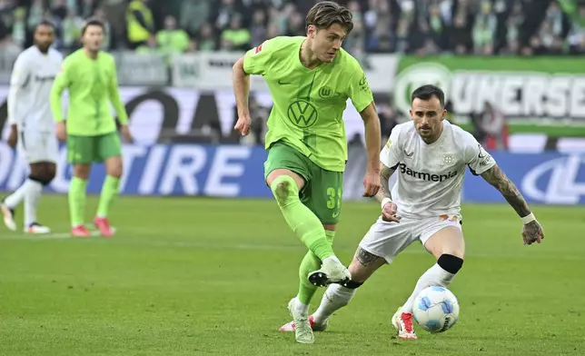 Wolfsburg's Mattias Svanberg, left, plays against Leverkusen's Aleix Garcia during the German Bundesliga soccer match between VfL Wolfsburg and Bayer Leverkusen at the Volkswagen Arena in Wolfsburg, Germany, Saturday, Feb. 8, 2025. (Swen Pfortner/dpa via AP)
