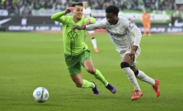 Leverkusen's Nathan Tella, right, plays against Wolfsburg's Kilian Fischer during the German Bundesliga soccer match between VfL Wolfsburg and Bayer Leverkusen at the Volkswagen Arena in Wolfsburg, Germany, Saturday, Feb. 8, 2025. (Swen Pfortner/dpa via AP)