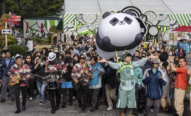 Visitors enter the panda enclosure to meet the Hong Kong-born giant panda twin cubs as they make their debut appearance to public in Ocean Park in Hong Kong, Sunday, Feb. 16, 2025. (AP Photo/Chan Long Hei)