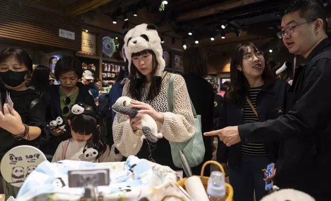 Visitors shop at a panda-themed store in Ocean Park as the Hong Kong-born giant panda twin cubs make their debut appearance to public in Hong Kong, Sunday, Feb. 16, 2025. (AP Photo/Chan Long Hei)