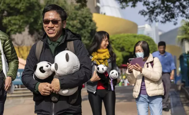 Visitors hold panda soft toy to enter the panda enclosure to meet the Hong Kong-born giant panda twin cubs as they make their debut appearance to public in Ocean Park in Hong Kong, Sunday, Feb. 16, 2025. (AP Photo/Chan Long Hei)