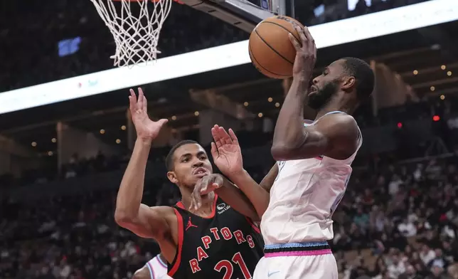 Miami Heat's Andrew Wiggins (22) gathers the ball in front of Toronto Raptors' Orlando Robinson (21) during first half NBA basketball action in Toronto on Friday, February 21, 2025. (Chris Young/The Canadian Press via AP)