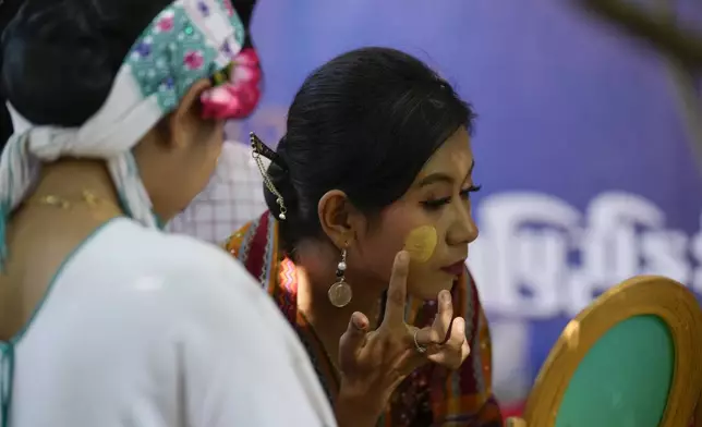 Artists with traditional attire put Thanakha, traditional make-up, on their faces as they take part in performance competition show aiming to submit the traditional culture of Thanakha to UNESCO's Intangible Cultural Heritage of Humanity, Wednesday, Feb.12, 2025 in Yangon, Myanmar. (AP Photo/Thein Zaw)
