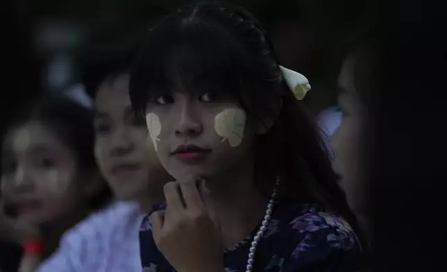 A girl puts Thanakha, traditional make-up, on her faces watches performance competition show aiming to submit the traditional culture of Thanakha to UNESCO's Intangible Cultural Heritage of Humanity, Wednesday, Feb.12, 2025 in Yangon, Myanmar. (AP Photo/Thein Zaw)