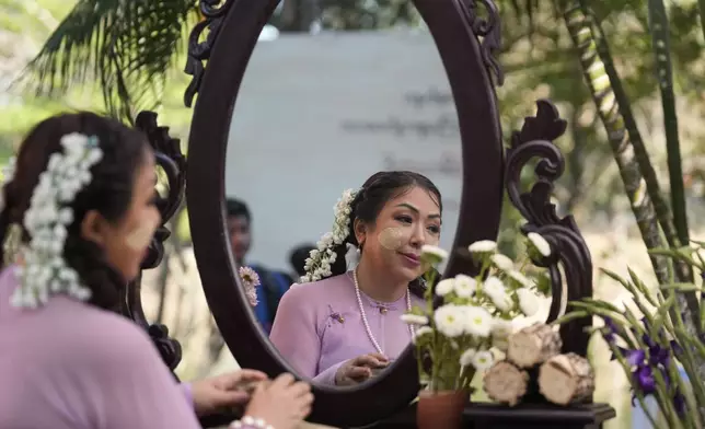 Artist with traditional attire put Thanakha, traditional make-up, on her face as they take part in performance competition show aiming to submit the traditional culture of Thanakha to UNESCO's Intangible Cultural Heritage of Humanity, Wednesday, Feb.12, 2025 in Yangon, Myanmar. (AP Photo/Thein Zaw)