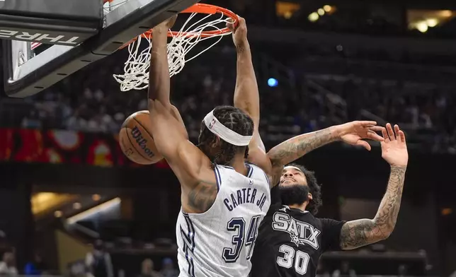 Orlando Magic center Wendell Carter Jr. (34) dunks over San Antonio Spurs forward Julian Champagnie (30) during the first half of an NBA basketball game Saturday, Feb. 8, 2025, in Orlando, Fla. (AP Photo/John Raoux)