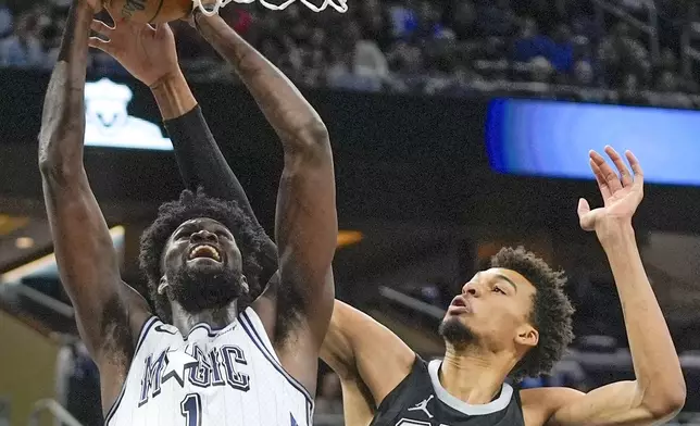 Orlando Magic forward Jonathan Isaac, left, makes a shot in front of San Antonio Spurs center Victor Wembanyama during the first half of an NBA basketball game Saturday, Feb. 8, 2025, in Orlando, Fla. (AP Photo/John Raoux)