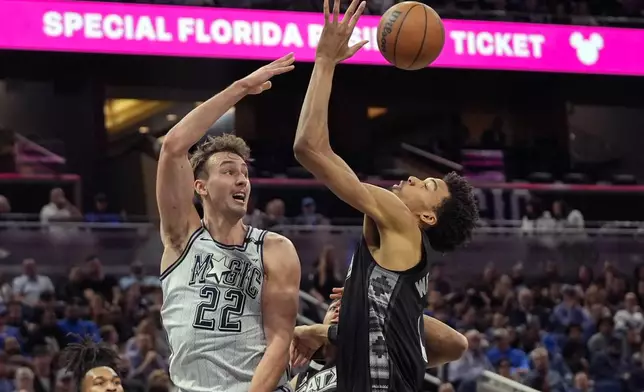 Orlando Magic forward Franz Wagner (22) passes the ball over San Antonio Spurs center Victor Wembanyama during the first half of an NBA basketball game Saturday, Feb. 8, 2025, in Orlando, Fla. (AP Photo/John Raoux)