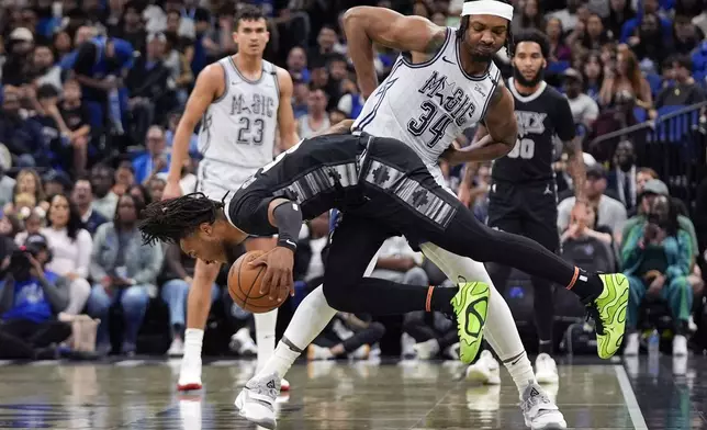 San Antonio Spurs guard Stephon Castle, front left, grabs a loose ball in front of Orlando Magic center Wendell Carter Jr. (34) during the first half of an NBA basketball game Saturday, Feb. 8, 2025, in Orlando, Fla. (AP Photo/John Raoux)