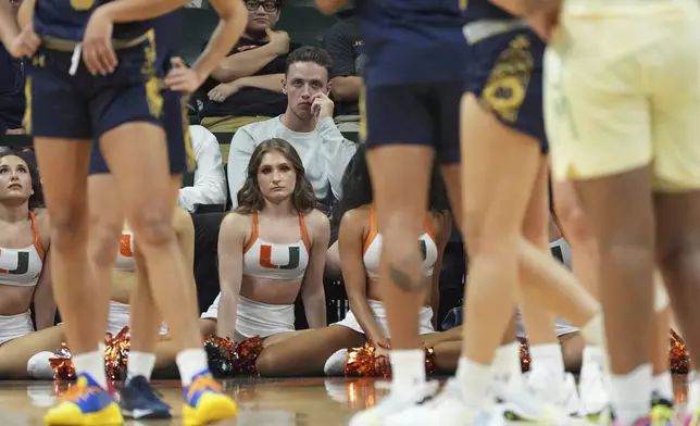 Miami football quarterback Carson Beck, center, watches the first half of an NCAA college basketball game between Miami and Notre Dame, Thursday, Feb. 20, 2025, in Coral Gables, Fla. (AP Photo/Rebecca Blackwell)