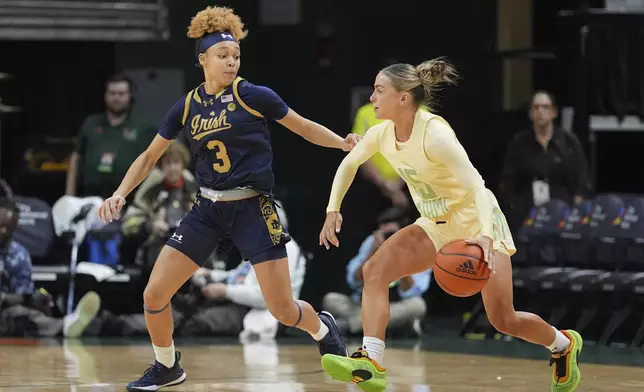 Miami guard Hanna Cavinder (15) drives forward, defended by Notre Dame guard Hannah Hidalgo (3), in the first half of an NCAA college basketball game, Thursday, Feb. 20, 2025, in Coral Gables, Fla. (AP Photo/Rebecca Blackwell)