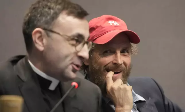 Don Giacomo Cardinali, left, and Italian artist Lorenzo Jovanotti Cherubini attend a press conference presenting the exhibition "En Route" organized by the Vatican Apostolic Library exploring world tours of the late 19th century at the Vatican, Friday, Jan. 31, 2025. (AP Photo/Gregorio Borgia)